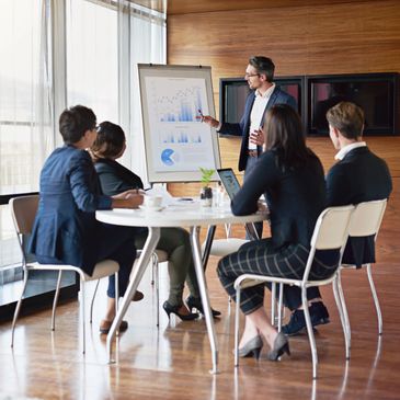 Businessman presenting charts to colleagues in a modern office meeting.