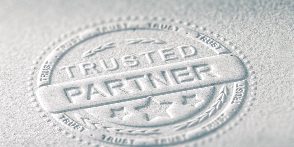 Embossed seal with the words 'Trusted Partner' and stars on textured paper.