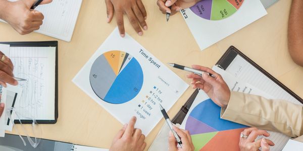 Team collaborating over colorful pie charts and notes in a business meeting.