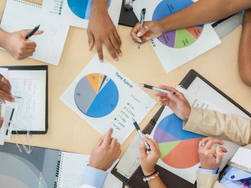People analyzing pie charts in a meeting.
