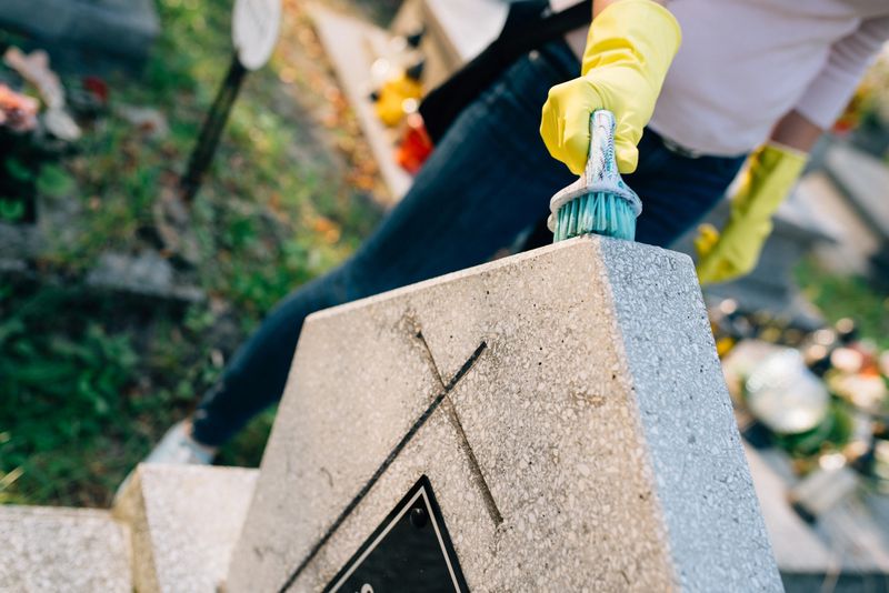 A woman cleans the grave. Washing tombstone with brush. Preparations for All Saints Day on November 1