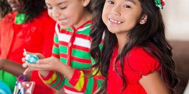 Three children in festive attire enjoying holiday crafts together.