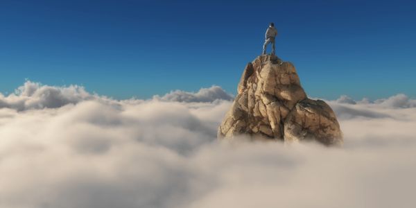 A man at the summit of a mountain above the clouds