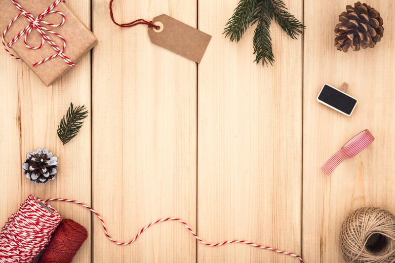Christmas background with gifts, string and pine cones. Top view with copy space. Natural style handcrafted gift box on wooden background. Packaging ideas.