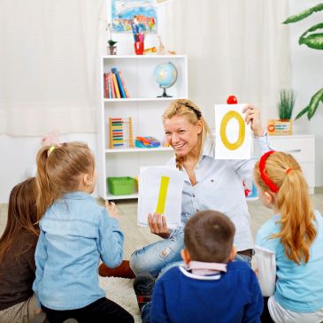 Teacher holding number cards with children.