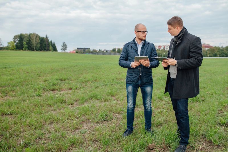 Two young investors are having a business meeting outside. Garden background.