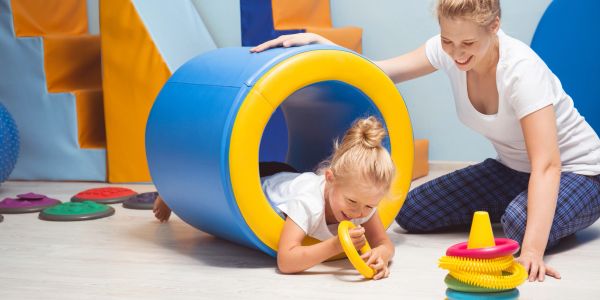 Child exiting play tunnel with adult nearby.