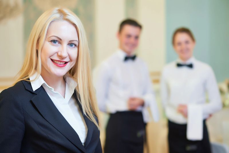 Catering services. Restaurant manager portrait in front of waiter and waitress staff at banquet hall during the event.