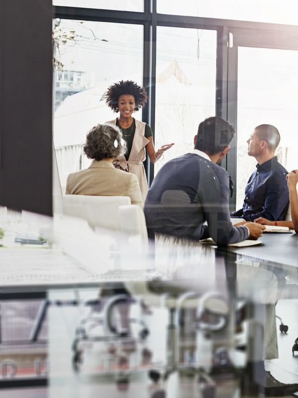 A woman presenting to a small group in a modern office setting.