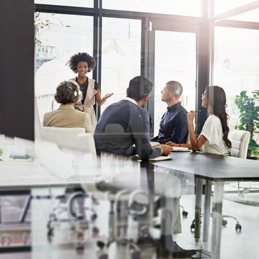 A woman leads a discussion in a modern office meeting with attentive colleagues.