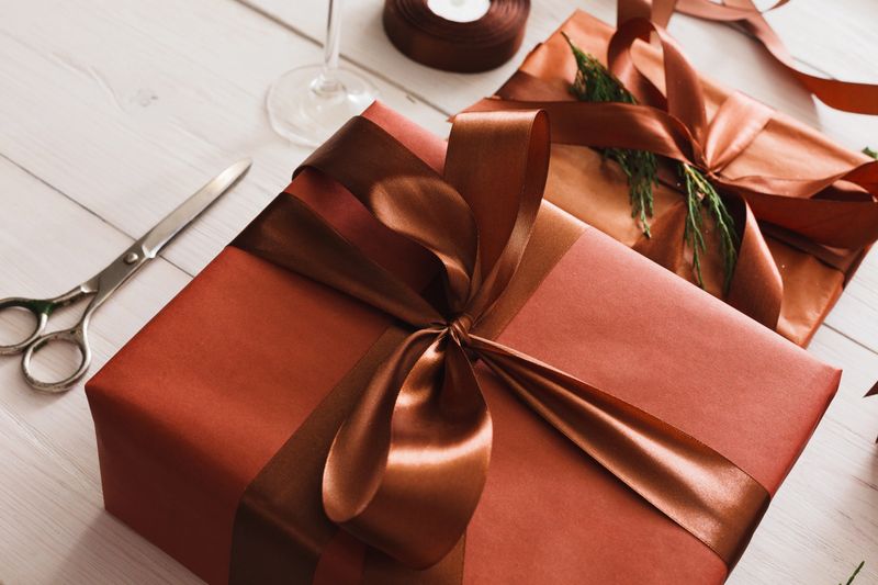 Gift wrapping background. Packaging stylish christmas present boxes in maroon paper decorated with satin ribbon bows. Christmas and winter holidays concept. Still life