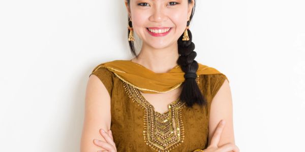 Smiling woman in traditional attire with braided hair.