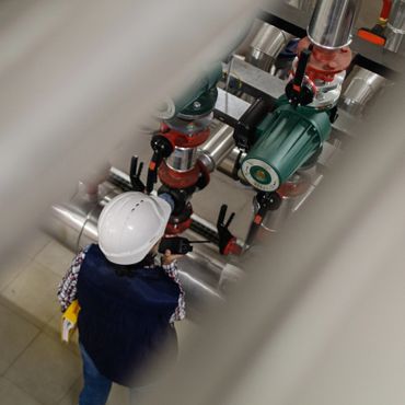Engineer inspecting industrial piping system while communicating on a walkie-talkie.