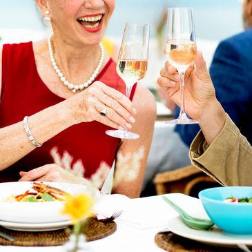 Two people toasting with wine glasses at a meal.