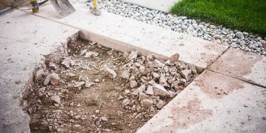 Concrete sidewalk partially broken up with tools nearby.