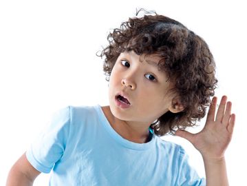 Curly-haired child listening intently with hand cupped to ear.
