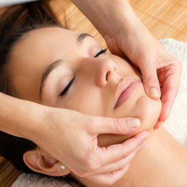 Woman receiving a relaxing facial massage with closed eyes.
