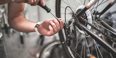 Person repairing a bicycle gear with a screwdriver.