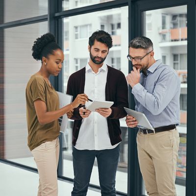 Three colleagues collaborate using digital tablets in a modern office.