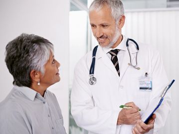 Doctor consulting with an elderly patient in a clinical setting.