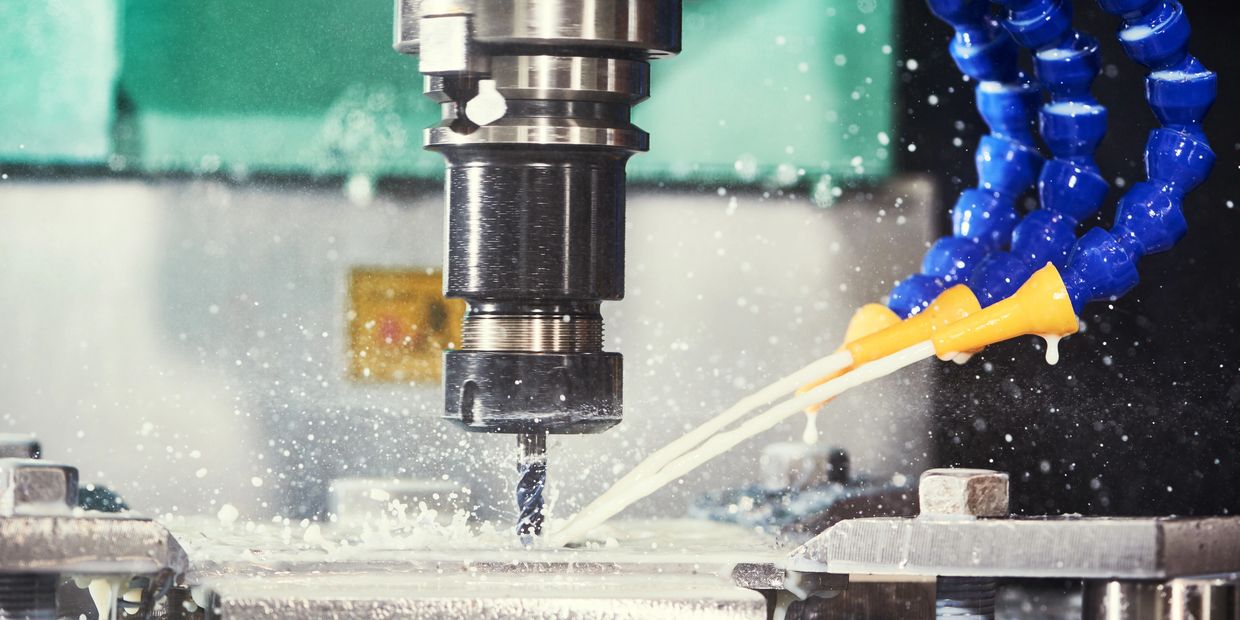 CNC milling machine cutting metal with coolant spray.