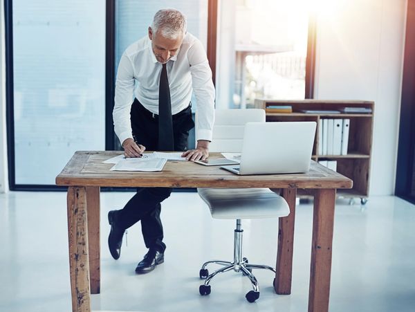 Businessman reviewing documents at a wooden desk in a bright office.