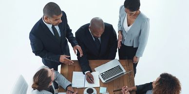 A group of people looking at a laptop and writing notes