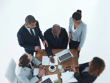 Business team discussing documents around a table with a laptop and coffee.