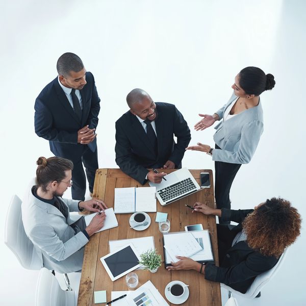 Five diverse professionals collaborating around a wooden table in a business meeting.