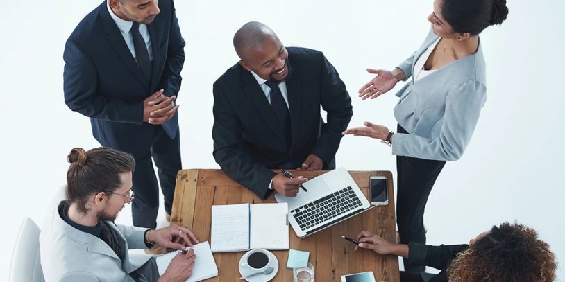 Five diverse professionals collaborating around a wooden table in a business meeting.