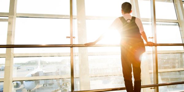Man looking out of a large delux window towards a cityscape and sunset