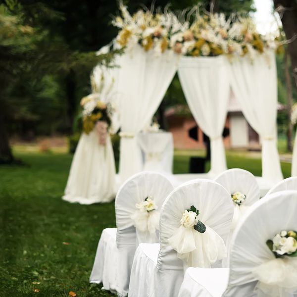 Elegant outdoor wedding setup with white chairs and floral decorations.