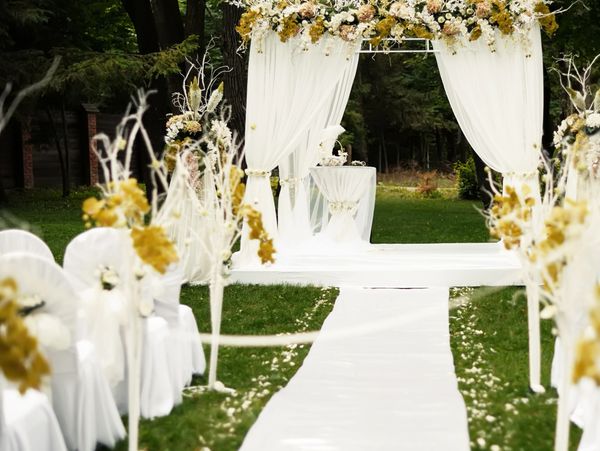 Elegant outdoor wedding aisle with white and gold floral decorations.