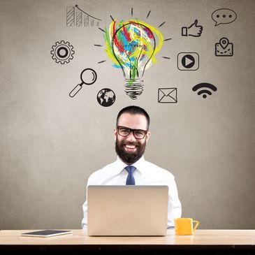Smiling man with laptop and creative digital icons above his head.