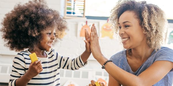 Child and adult giving a high-five while playing with colorful blocks.
