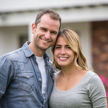 Smiling couple standing close together outdoors in casual clothes.