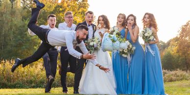 A man dramatically lunges to catch a falling wedding cake as the bridal party watches in shock.