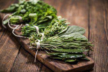 Bundles of fresh herbs tied with string on a wooden board.