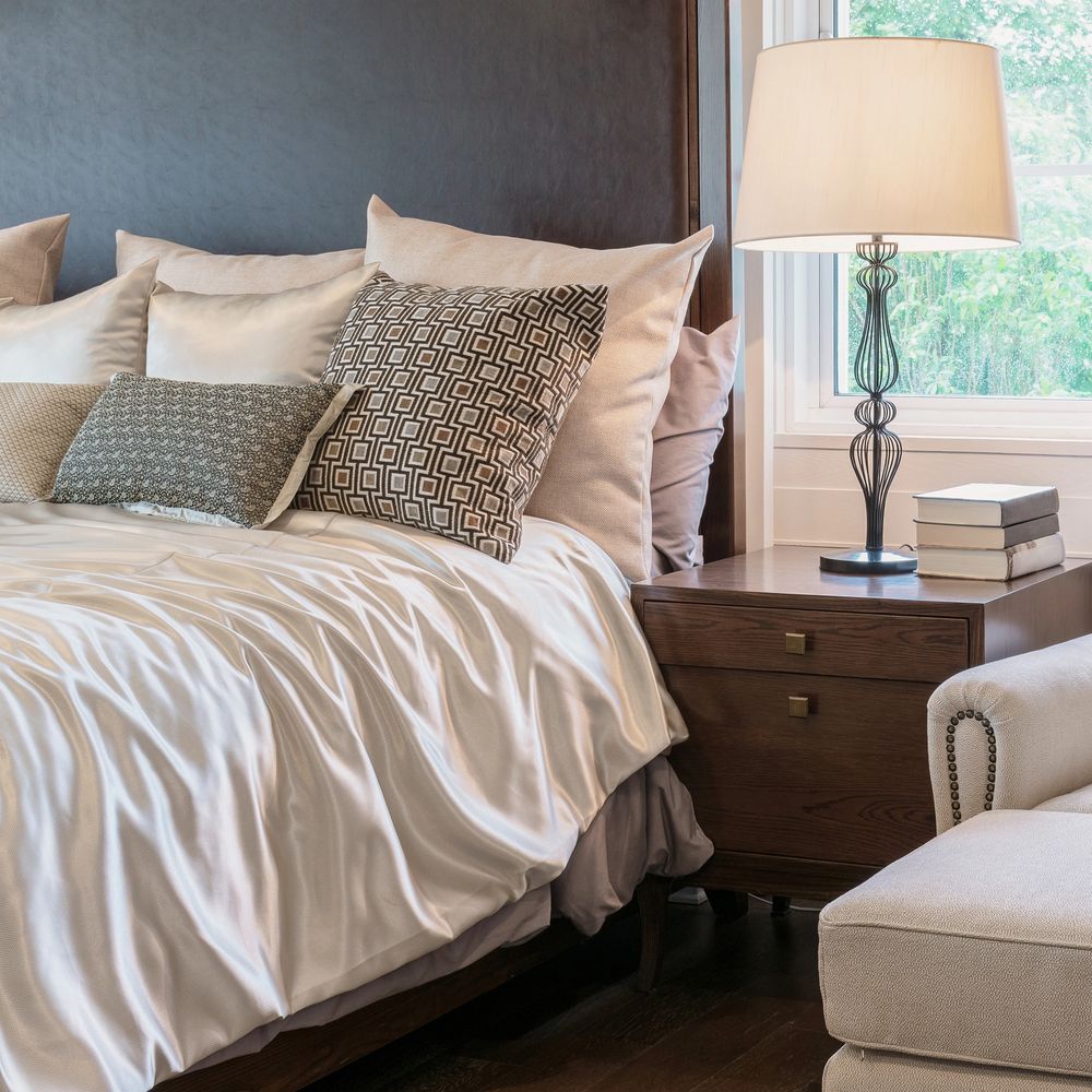 Elegant bedroom setup with a cozy bed, patterned pillows, and a bedside lamp.