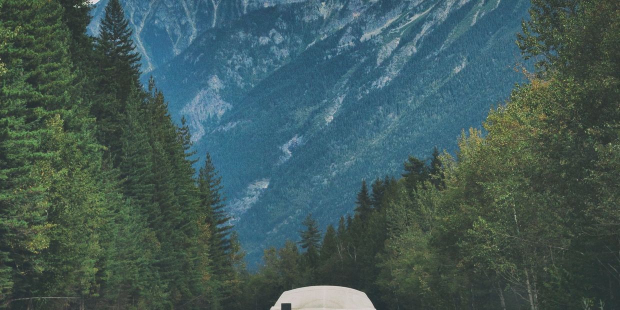 Boat being towed on a mountain highway surrounded by trees.