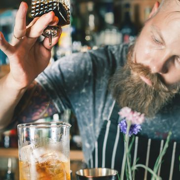 a man dresses up and handing you a bottle of premium spirits
