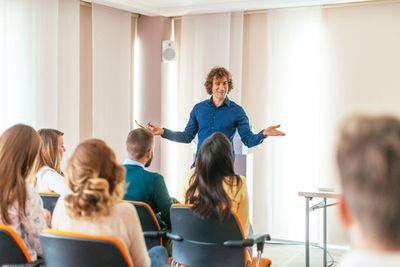 Man giving a presentation to a seated audience in a bright room.