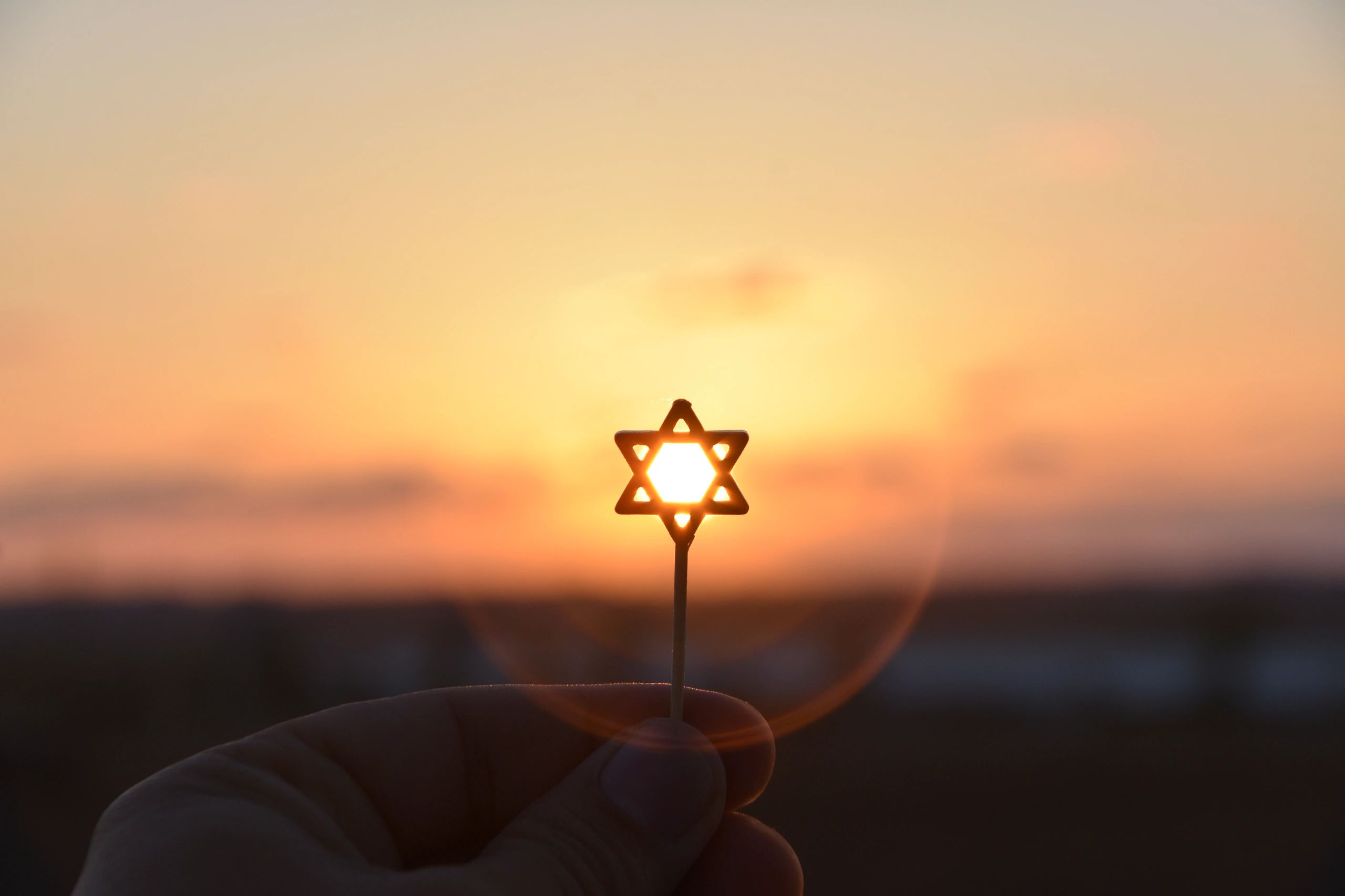 Star of David held against a sunset.