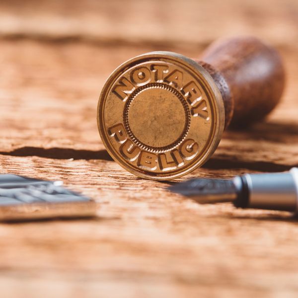 A notary public stamp and pen on a wooden surface.