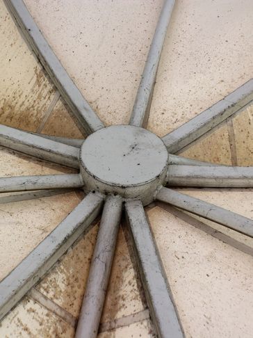 Close-up of a dirty, geometric ceiling structure with radial beams.