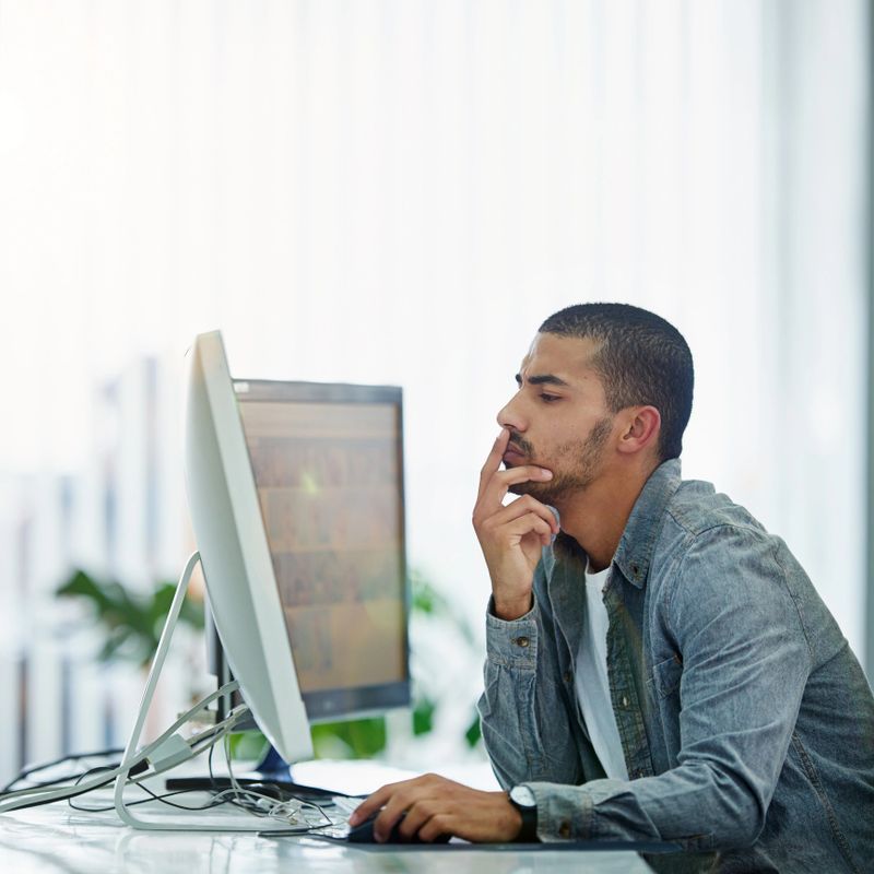 Shot of a young designer deep in thought while working on a computer in a modern office