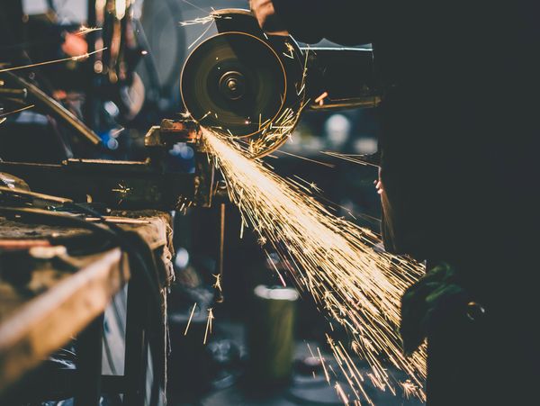 Worker using a grinder, sparks flying in a workshop.