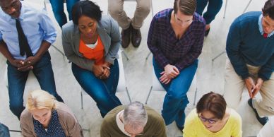Diverse group of people seated in a circle, engaged in discussion or meeting.