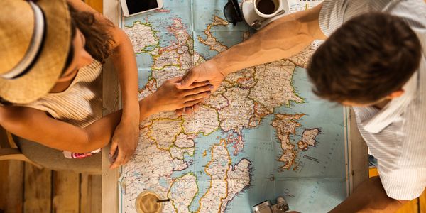 Couple planning a trip together over a map with coffee and camera.