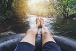 Relaxing feet dipped in a forest stream with sunlight.